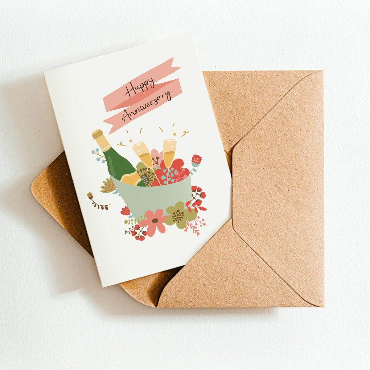 Greeting card with 'Happy Anniversary' text and illustrations of bottles and flowers, placed inside a brown envelope on a white background.