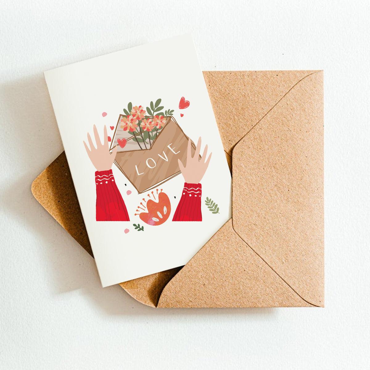 Greeting card with illustration of hands holding a box labeled 'LOVE' and a brown envelope on a white background.