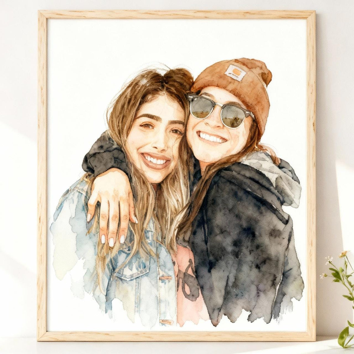 Framed watercolor painting of two people embracing on a white wall.