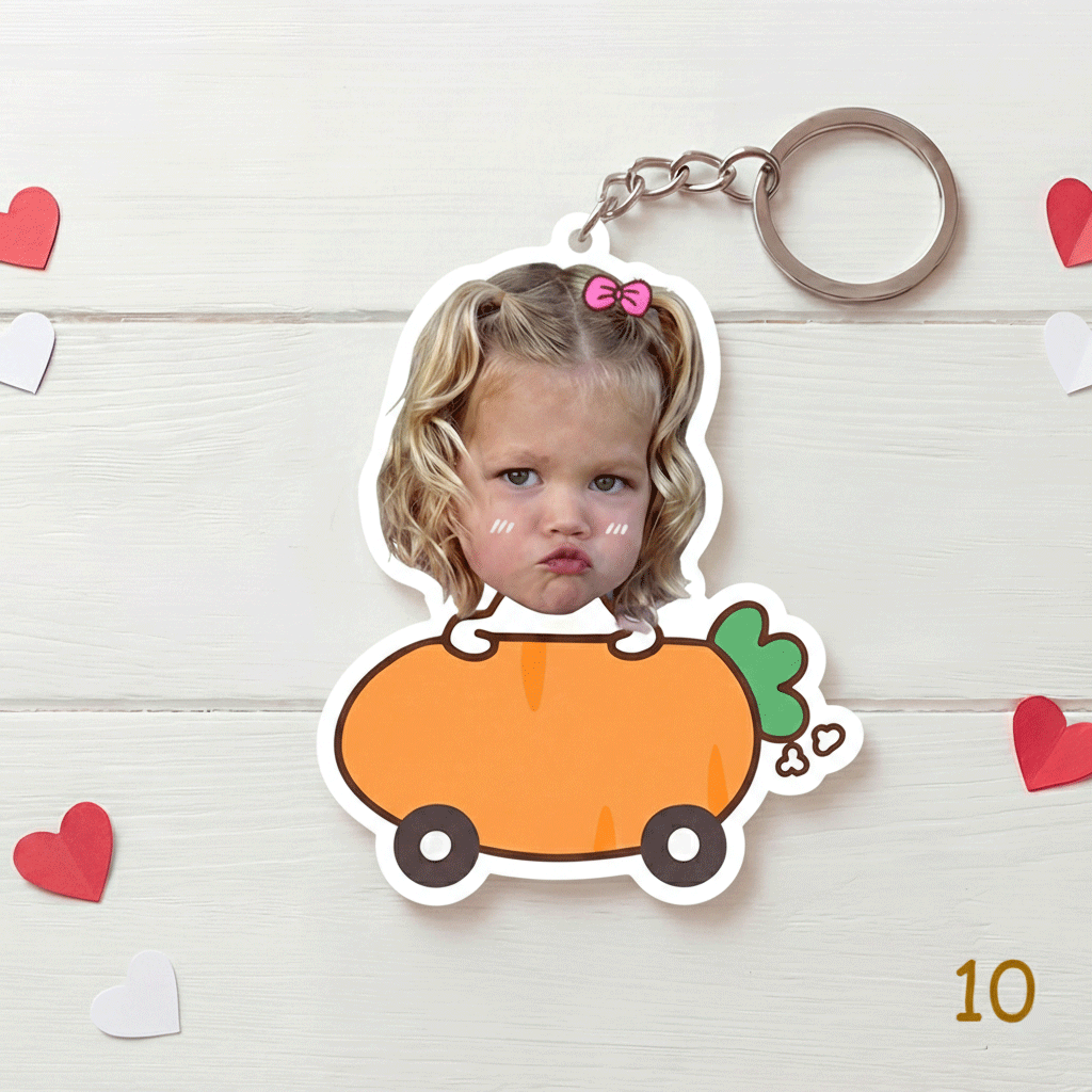 Keychain with a design of a child's face on a carrot, surrounded by heart decorations on a wooden surface.