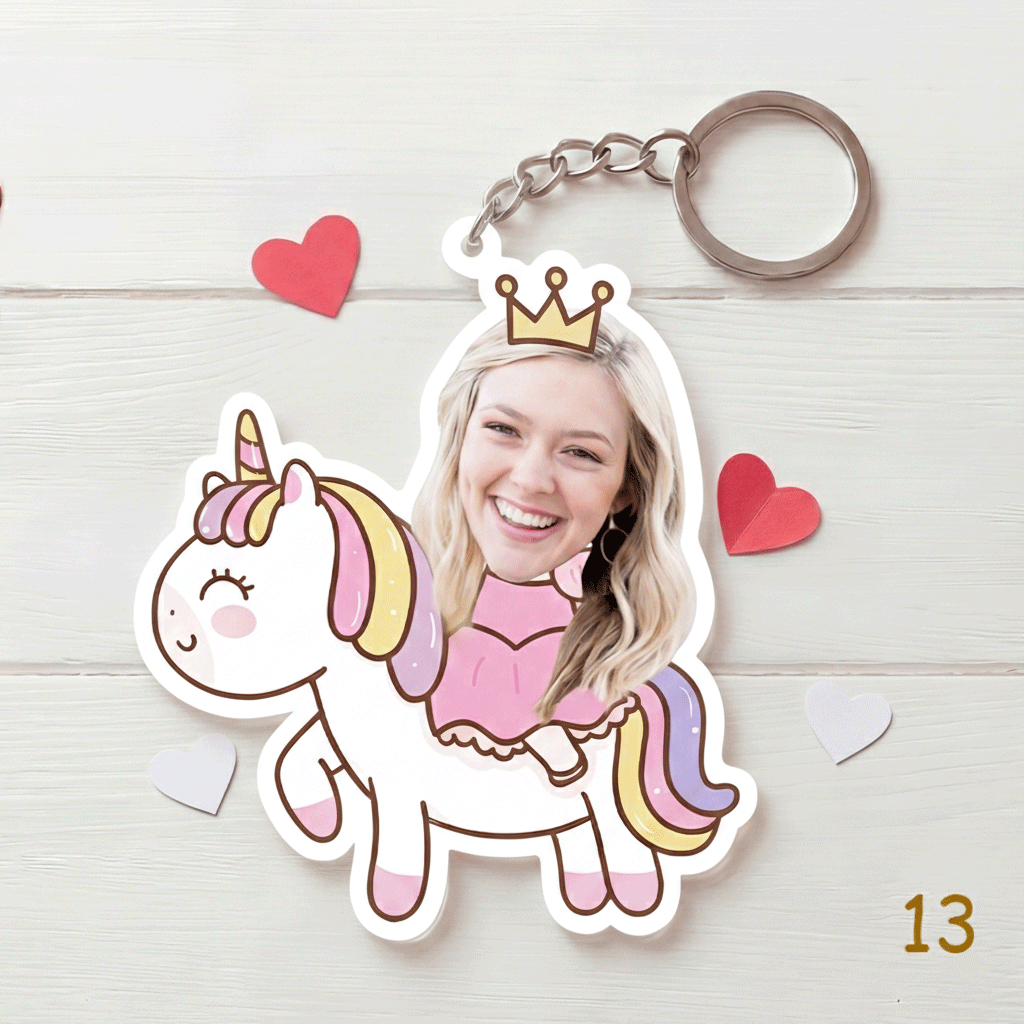 Keychain with a cartoon unicorn and person's face, surrounded by heart shapes on a light wooden background.