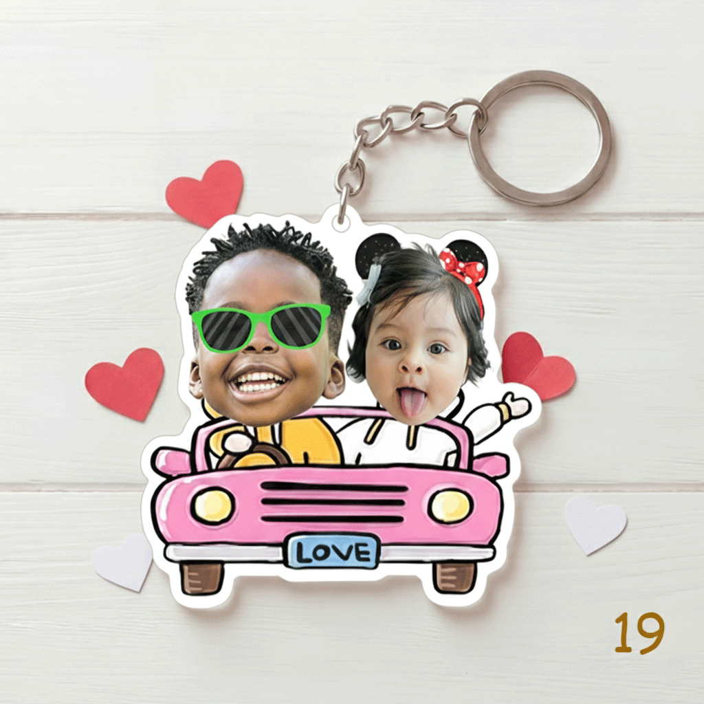 Keychain with cartoon design of two children in a car, surrounded by hearts on a light wooden background.