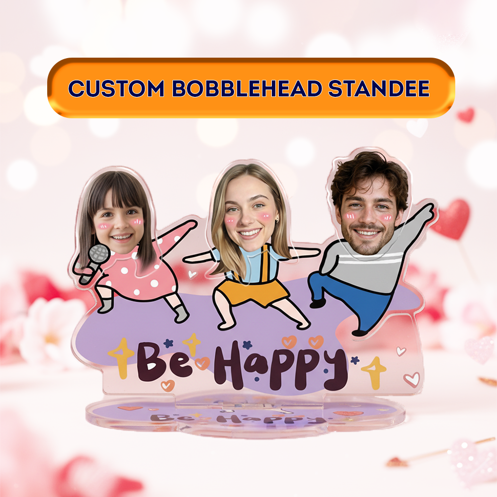 Custom bobblehead standee featuring a personalized family design with three cartoon-style figures, smiling faces, and the text “Be Happy,” displayed on a cute acrylic base