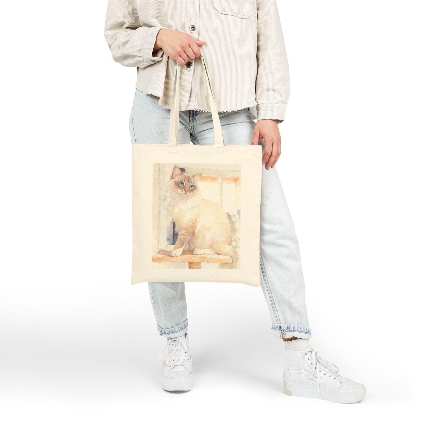 Person holding a tote bag with a cat design on a white background