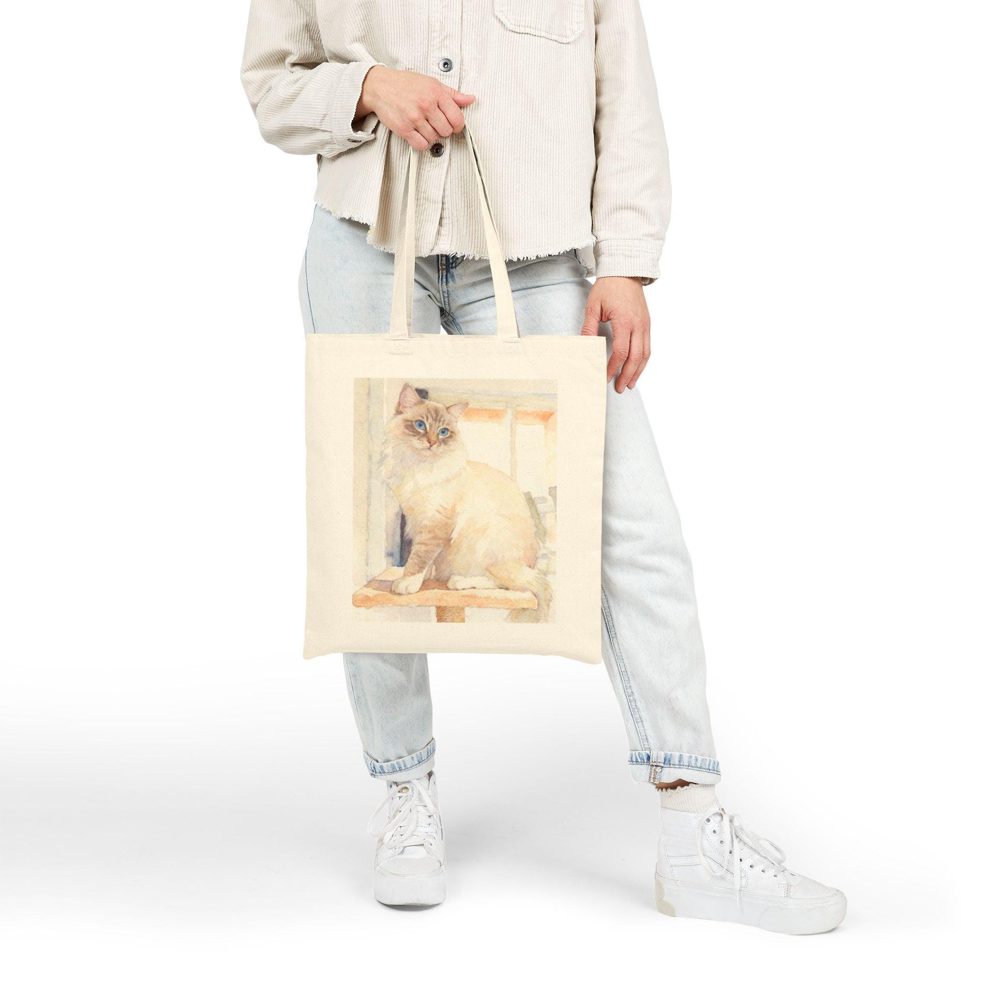 Person holding a tote bag with a cat design on a white background