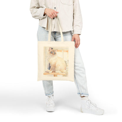 Person holding a tote bag with a cat design on a white background