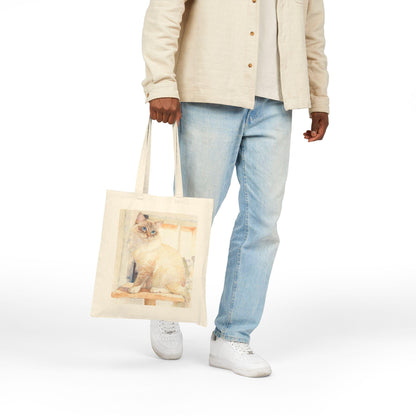 Person holding a tote bag with a cat design on a white background
